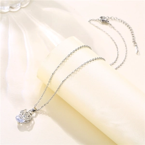 Macro detail of silver rose pendant with clear zircon on delicate chain necklace