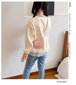 Detail of pink girls' crossbody bag with pearl bow decoration on a child model