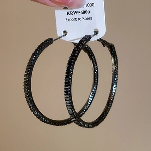 Macro shot of large black hoop earrings featuring pave-set square-cut black zircons