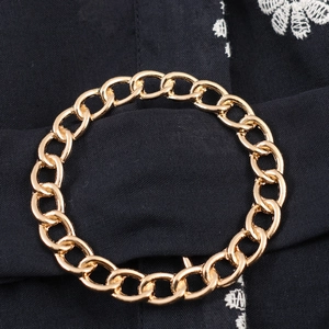 Elegant gold link chain bracelet displayed on black embroidered fabric background