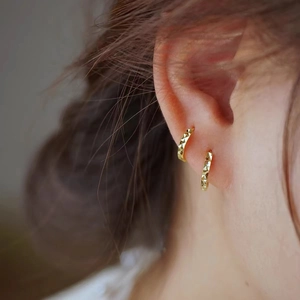 Close-up of S925 silver gold-plated faceted hoop earrings on female model's ear