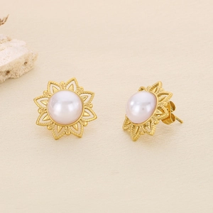 Macro shot of sun flower pearl stud earrings with gold plating on beige textured paper