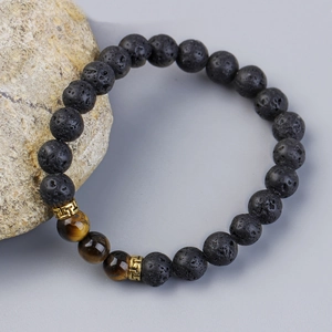 Volcano lava stone and tiger eye bead bracelet with golden cloud charms on a rock display