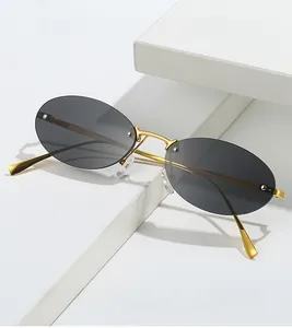 Detail of rimless oval sunglasses with sleek gold metal temples and dark gray lenses