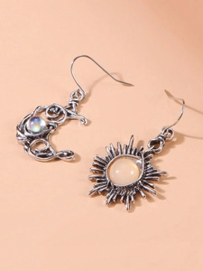 Makroaufnahme von Silberohrringen mit Sonne, Mond und opalisierenden Perlen im Boho-Stil