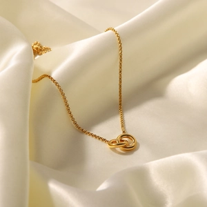 Interlocked double ring pendant necklace in gold-plated titanium steel on white satin
