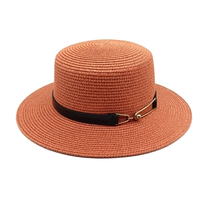 Close-up of terracotta straw hat weave texture with black band and gold buckle