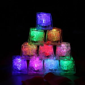 Close-up of multicolored LED glowing ice cubes stacked in a pyramid on black background