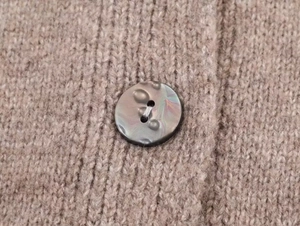 Macro view of a marbled round button on brown ribbed knit wool texture cardigan