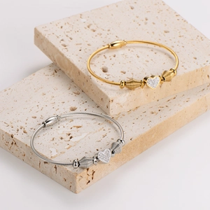 Dual-tone stainless steel cable heart bracelets with sparkling crystal pavé on stone stand