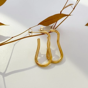 Macro shot of abstract wavy gold earrings with glossy enamel and geometric twist lines