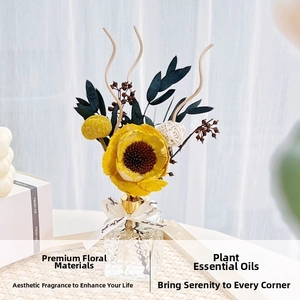 Detail of a reed diffuser set with yellow dried flowers and a ribbon-tied glass bottle