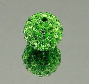 Macro shot of a green clay rhinestone bead with crystals on a reflective surface