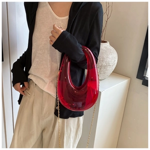 Detail of red acrylic U-shaped clutch bag with detachable golden chain strap and handle