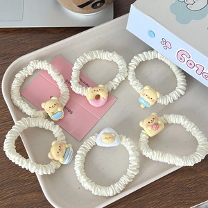 Détail de 6 chouchous crème avec adorables breloques ours dans un plateau de présentation