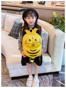 Detail of yellow bee-shaped toddler backpack with cute cartoon shell on a wooden surface