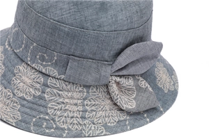 Detailed view of grey-blue sun hat featuring beige floral embroidery and a bow