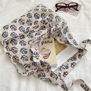 Close-up of vintage floral canvas tote bag with blue flowers on a white background