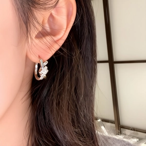 Close-up of silver knot hoop earrings with pavé zircons worn by a model in soft lighting