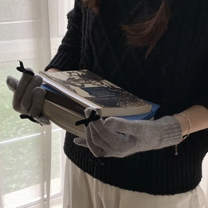 Detail of grey knitted gloves with black bow and touchscreen design for winter
