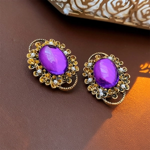 Macro shot of vintage gold earrings with oval purple stones and delicate pearl accents