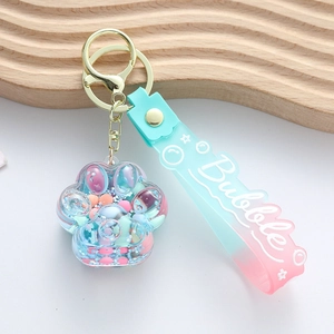 Porte-clés patte de chat dégradé rose et bleu avec paillettes sur plateau en bois