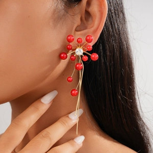 Detail of red bead and gold tassel earrings with zircon inlay worn by model