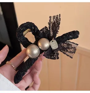 Détail d'une pince à cheveux élégante en dentelle noire avec perles et pendentif chic