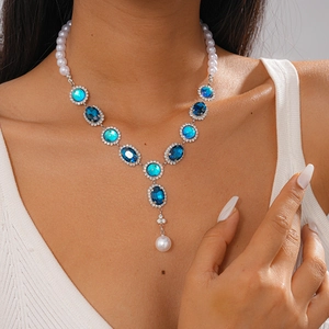 Close-up of vintage silver necklace featuring blue gemstones and pearls on model neck
