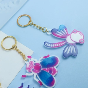 Détail de porte-clés DIY libellule et abeille en résine avec des chaînes dorées