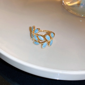 Detailansicht goldener Blattring mit hellblauem Emaille auf weißem Keramik