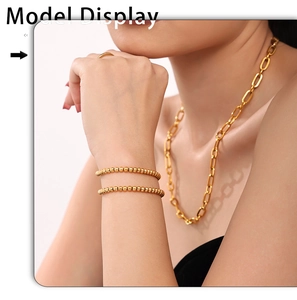 Detail view of 4mm gold beaded bracelets and oval link necklace on a model