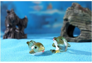 Detail of two mini resin dolphin figurines with translucent finish in underwater scenery