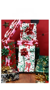 Close-up of pink bows and green snowflake patterns on festive Christmas wrapping paper rolls