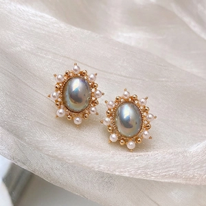 French vintage oval pearl earrings with gold base and iridescent center on white silk