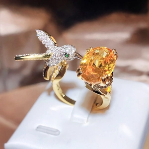 Exquisite gold hummingbird ring with oval yellow gemstone and white zircon accents