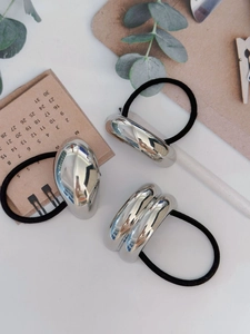 Close-up of minimalist silver metal hair ties with high-gloss mirror polish finish