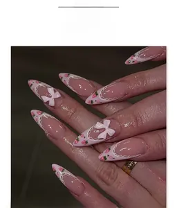 Detailed close-up of almond-shaped press-on nails with 3D bows and strawberry design