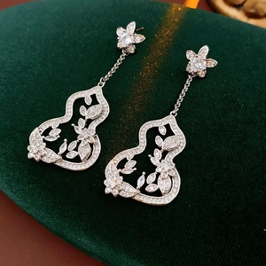 Détail de boucles d'oreilles fleur et gourde en argent avec zircon sur velours