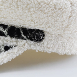 Détail du chapeau en laine d'agneau blanche avec bouton ancre en métal et ruban décoratif
