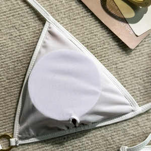 Detail of white triangle bikini top showing removable padding and golden metal ring