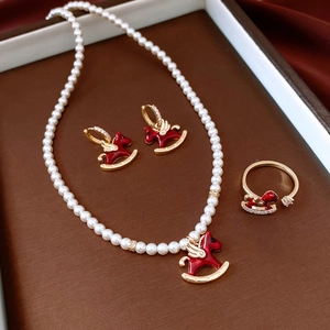 Detail view of pearl necklace and horse pendant jewelry set on red silk fabric background