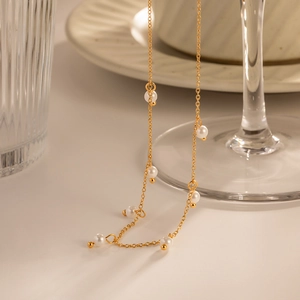 Detail of 18K gold stainless steel chain necklace with white pearls on glass