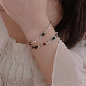Detail of layered bohemian bracelet with colorful natural stones and silver beads on wrist