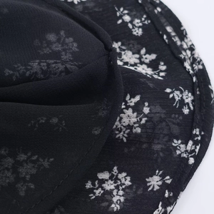 Macro detail of breathable black fabric with delicate white floral patterns and precise stitching