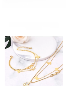 Detail view of 18k gold titanium steel bracelet featuring shell butterfly charms on marble