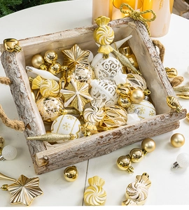 Detailed set of gold and white Christmas ornaments in a rustic wooden tray with warm lighting