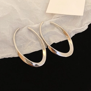 Macro shot of silver distorted oval hoop earrings with a polished metallic finish