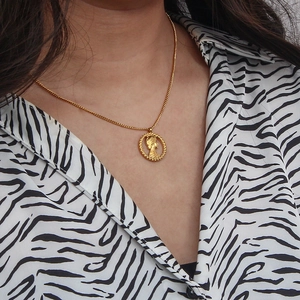 Detail of a vintage gold coin pendant featuring a queen portrait on a classic chain necklace