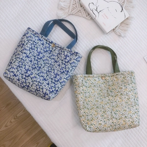 Floral canvas lunch bags in blue and yellow colors on a cozy quilted background